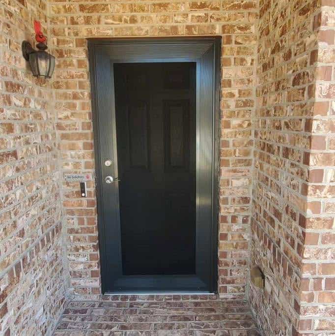 Bronze single front entry security screen door on brick porch in Arlington TX by Security Screen Masters of Texas