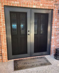 Dark bronze double French security screen doors installed on red brick home by Security Screen Masters of Texas