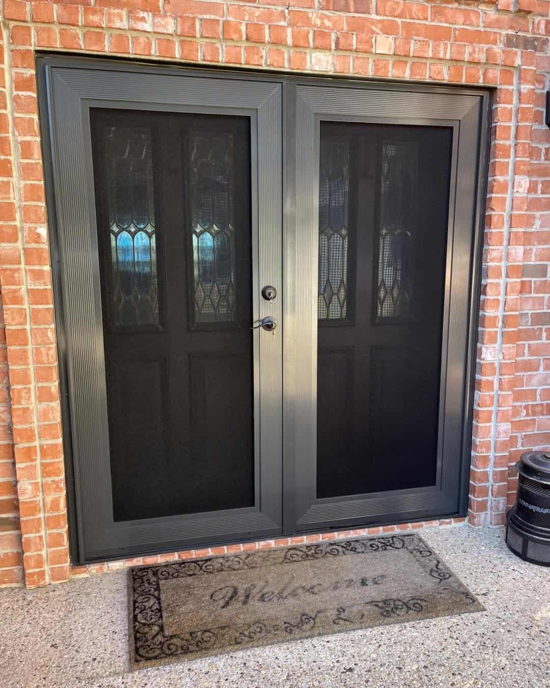 Dark bronze double French security screen doors installed on red brick home by Security Screen Masters of Texas