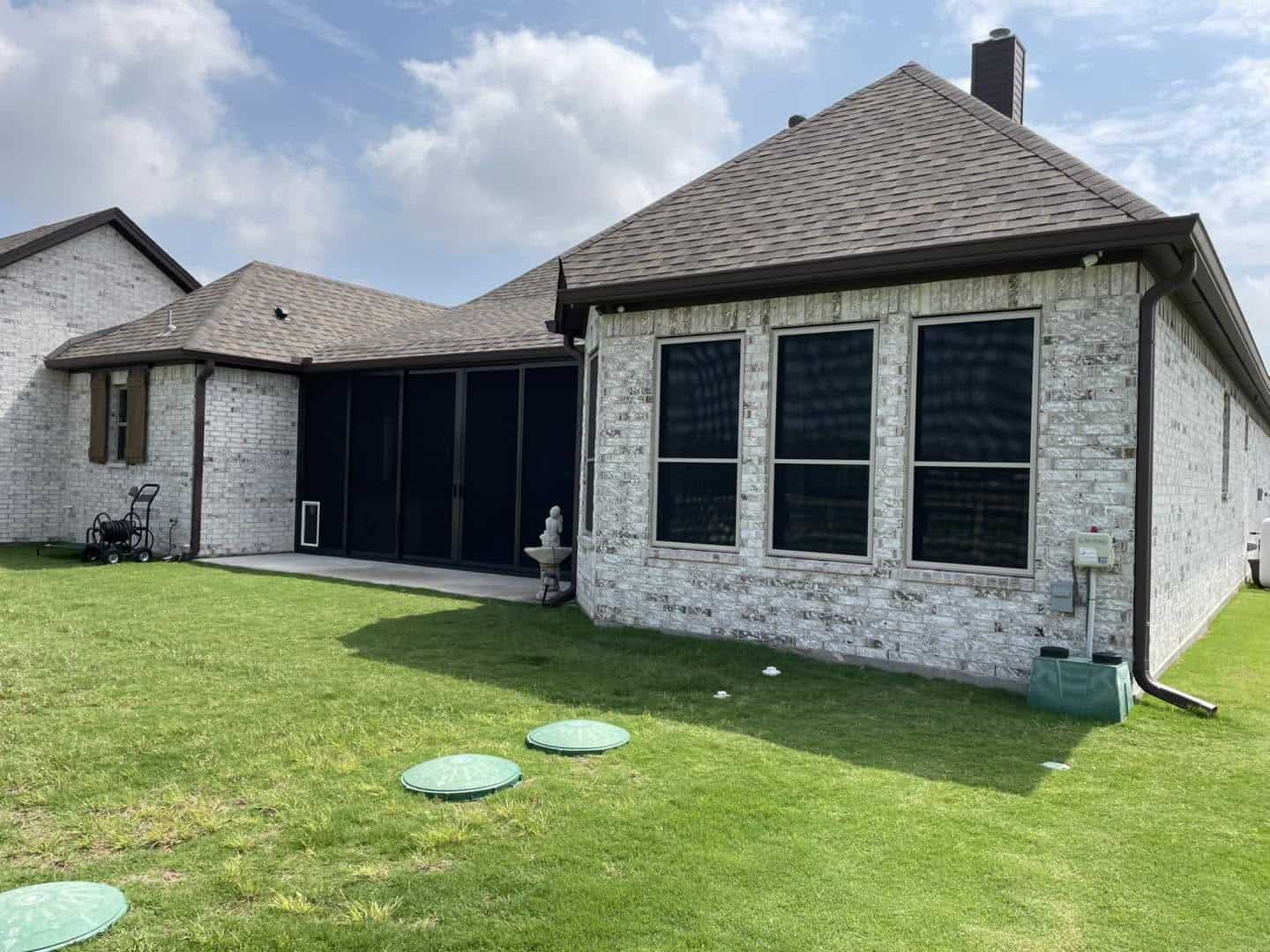 Three residential security window screens installed on light brick home in Plano TX by Security Screen Masters of Texas
