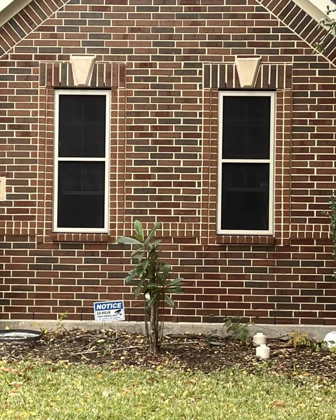 Security window screens with white frame installed on red brick home in Dallas TX by Security Screen Masters of Texas