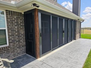 Stamped concrete patio security screen enclosure with sliding panels by Security Screen Masters of Texas
