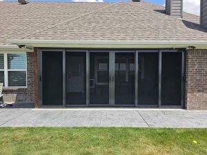 Full-width sliding patio security screen enclosure on stamped concrete by Security Screen Masters of Texas