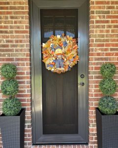Bronze front entry security screen door with autumn wreath on brick home by Security Screen Masters of Texas