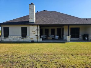 Rear facade security window screens on luxury Texas home with limestone chimney in Austin TX by Security Screen Masters of Texas
