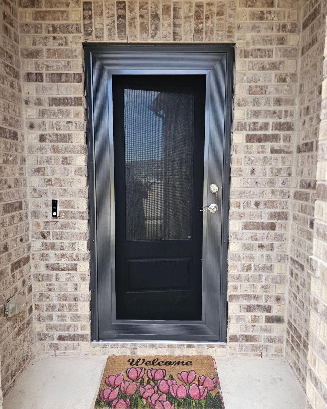 Front porch security screen door with floral welcome mat in Fort Worth TX by Security Screen Masters of Texas